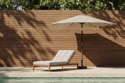 Beige lounge chair with umbrella by a poolside against a wooden wall