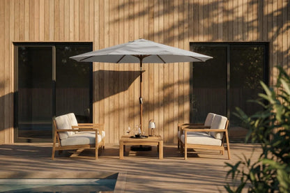 Outdoor patio set with two chairs, a table, and an umbrella against a wooden wall.