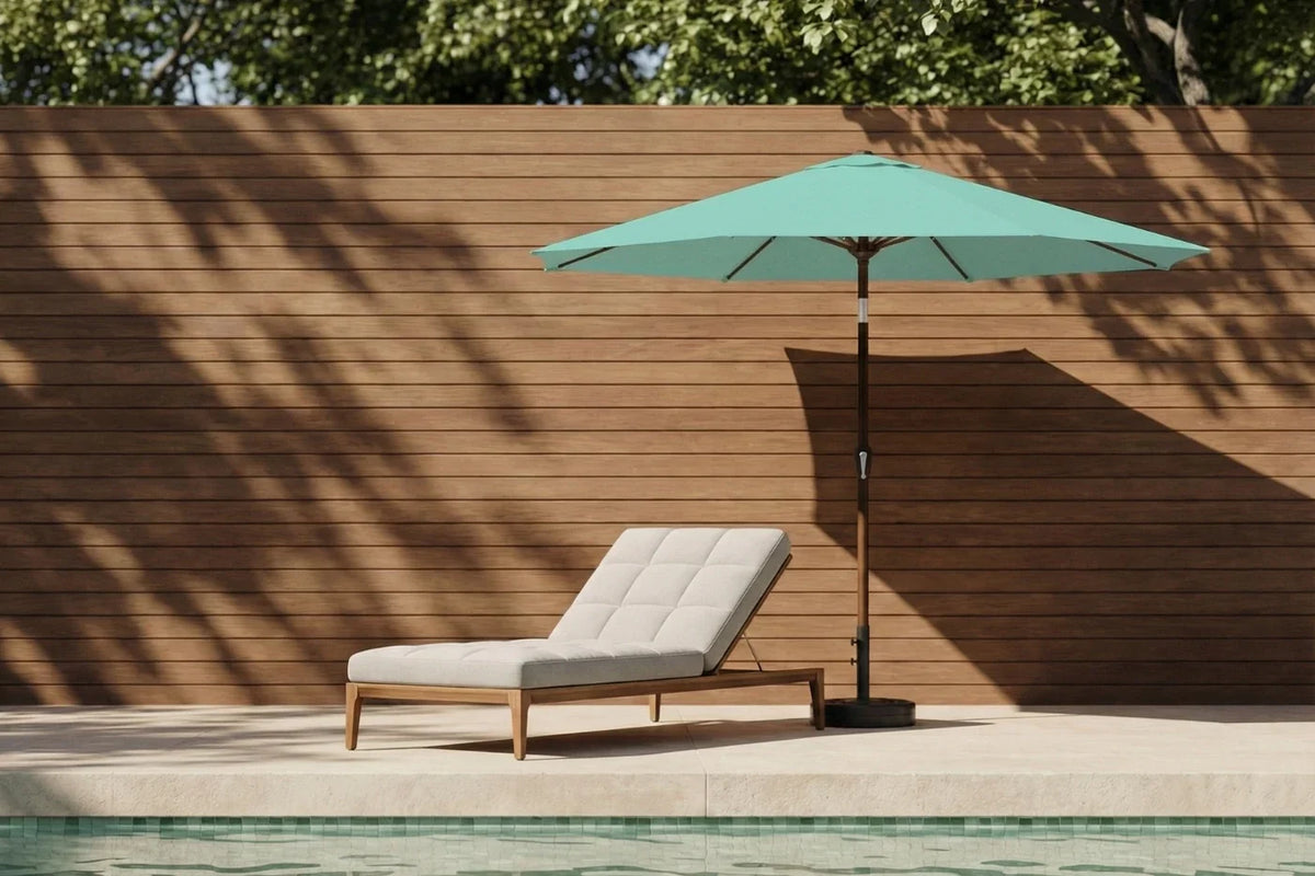 Chaise lounge with green umbrella by a poolside against a wooden wall