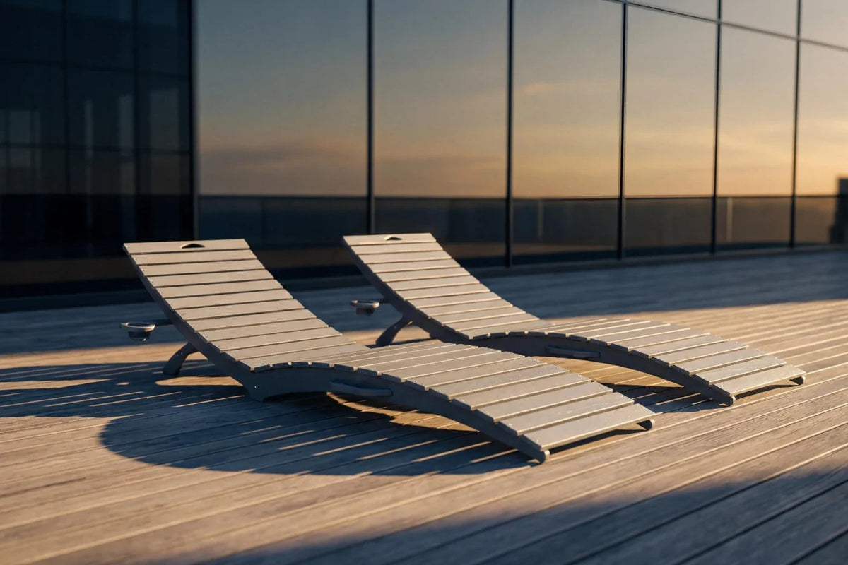 Two lounge chairs on a rooftop deck with a modern building in the background.