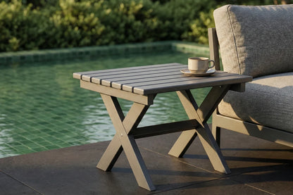 Outdoor table with a cup and saucer next to a couch by a pool