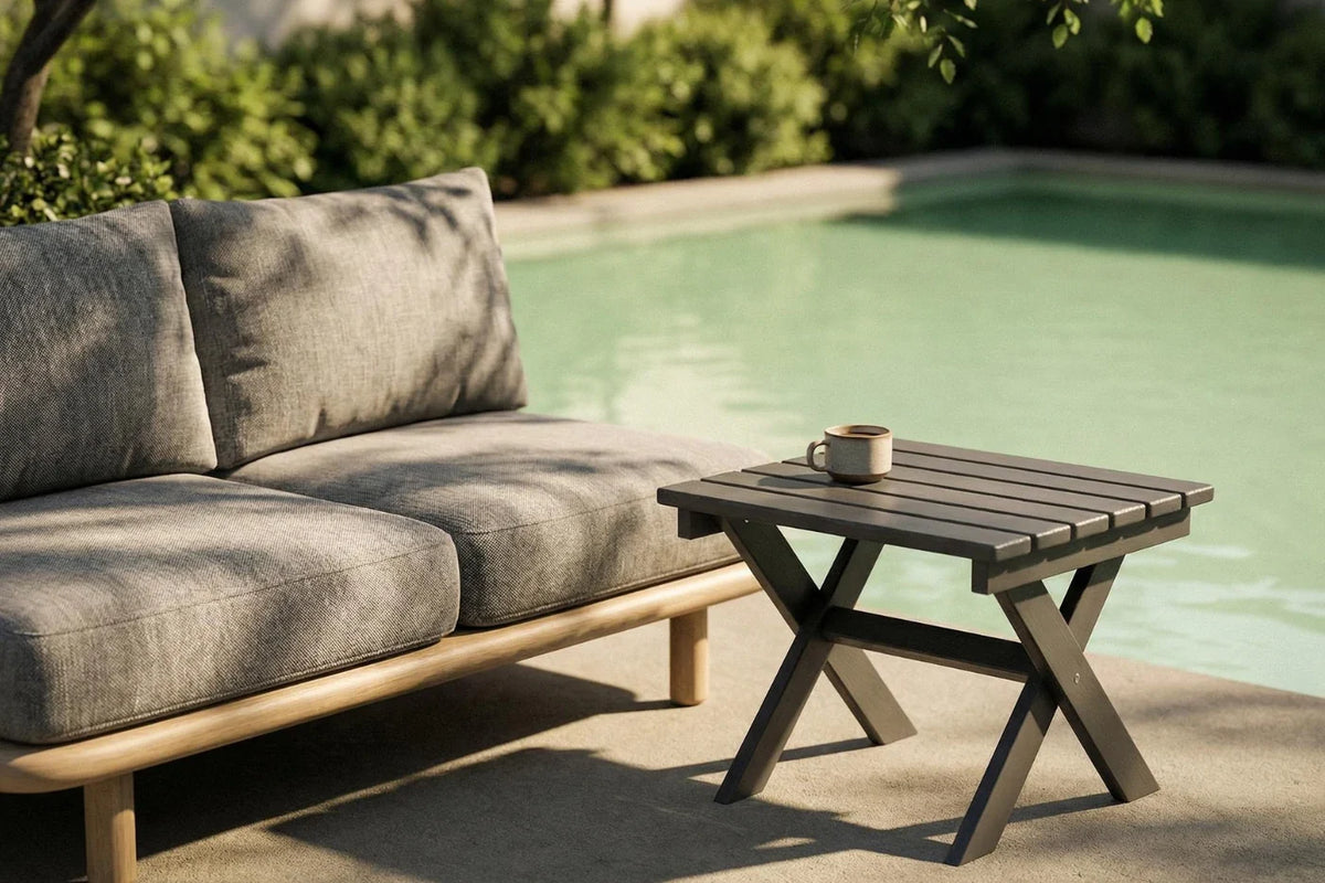 Outdoor setting with a gray sofa and wooden side table by a pool