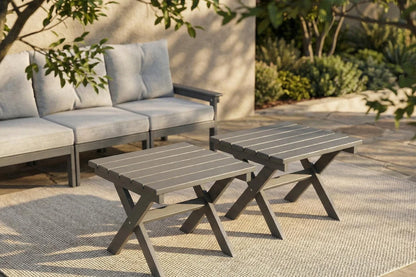 Outdoor patio set with gray sofa and matching tables on a patio.