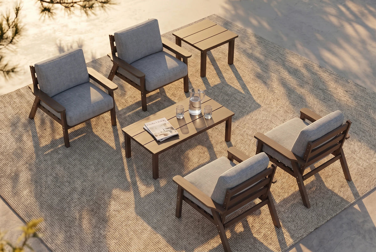 A 6-piece outdoor patio furniture set arranged on a textured beige rug. The set includes four armchairs with gray cushions and brown frames, one matching rectangular coffee table, and one matching side table.