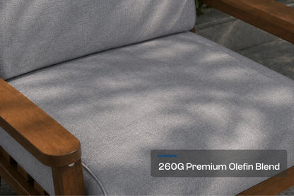 Close-up of a gray outdoor chair cushion with a brown frame, showing dappled sunlight and a text overlay that reads '260G Premium Olefin Blend'.